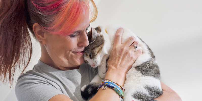 woman holds cat closely to cuddle